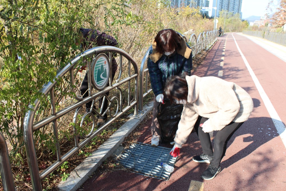 산책로 가장자리에 버려진 쓰레기를 줍고 있는 모습