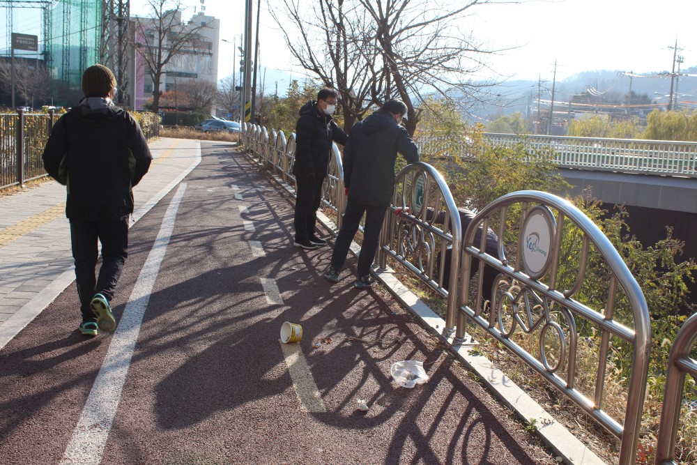 주민이 산책하고 있는 주변의 수풀에서 쓰레기를 찾아 모으는 모습